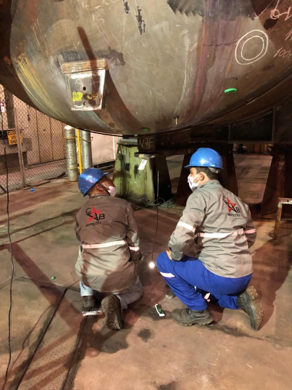Dois inspetores da CB Inspeções preparam o ensaio radiográfico sob um vaso de pressão na planta do cliente