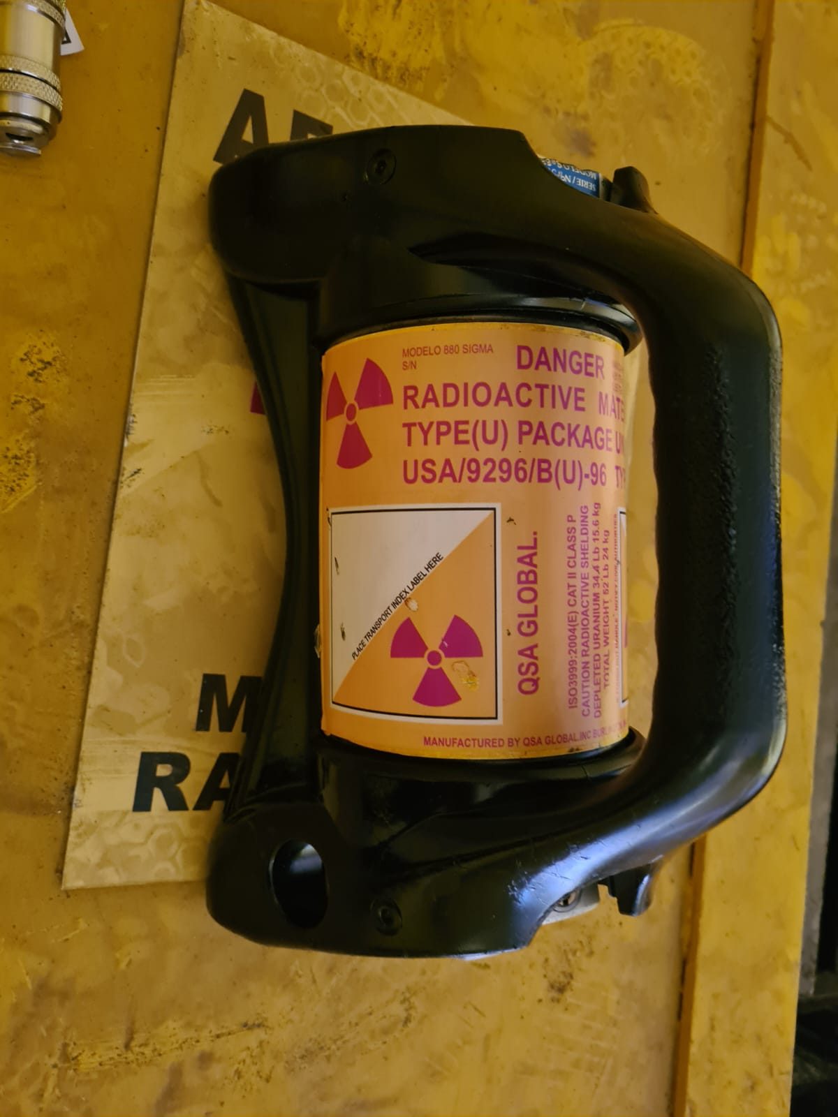 Irradiador gama com rótulo de embalagem para transporte de material radioativo, sobre base amarela